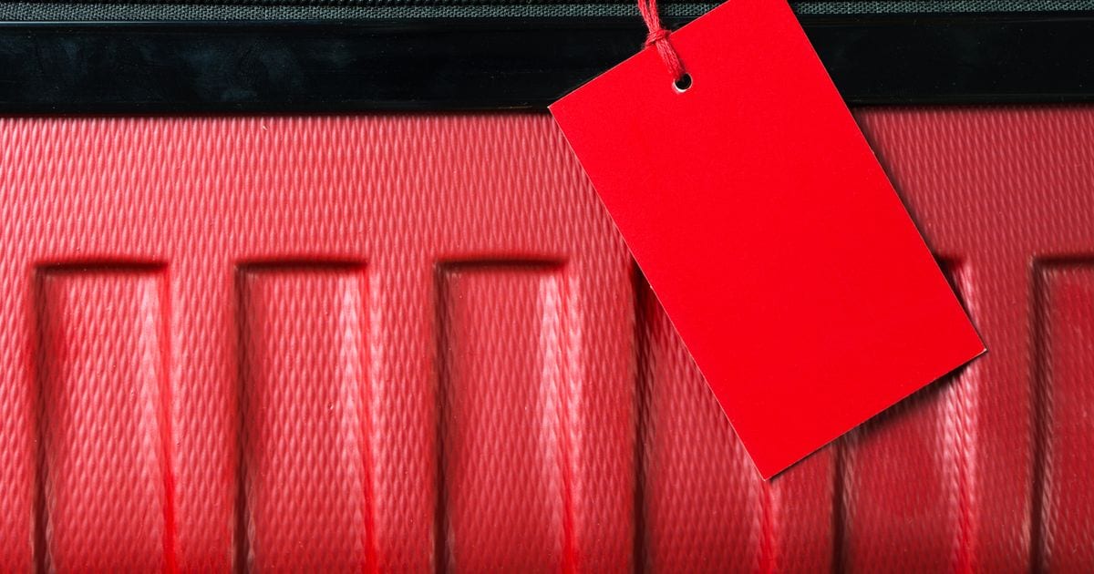A blank red tag hanging from a red suitcase