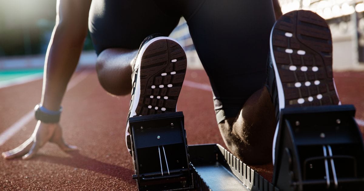 A sprinter's feet set in the starting blocks on a running track, before the start