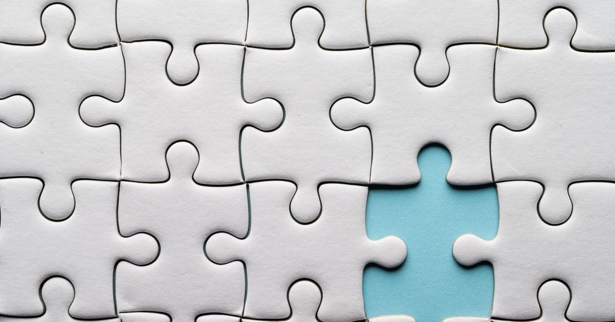 A white jigsaw puzzle with one piece missing, showing blue underneath