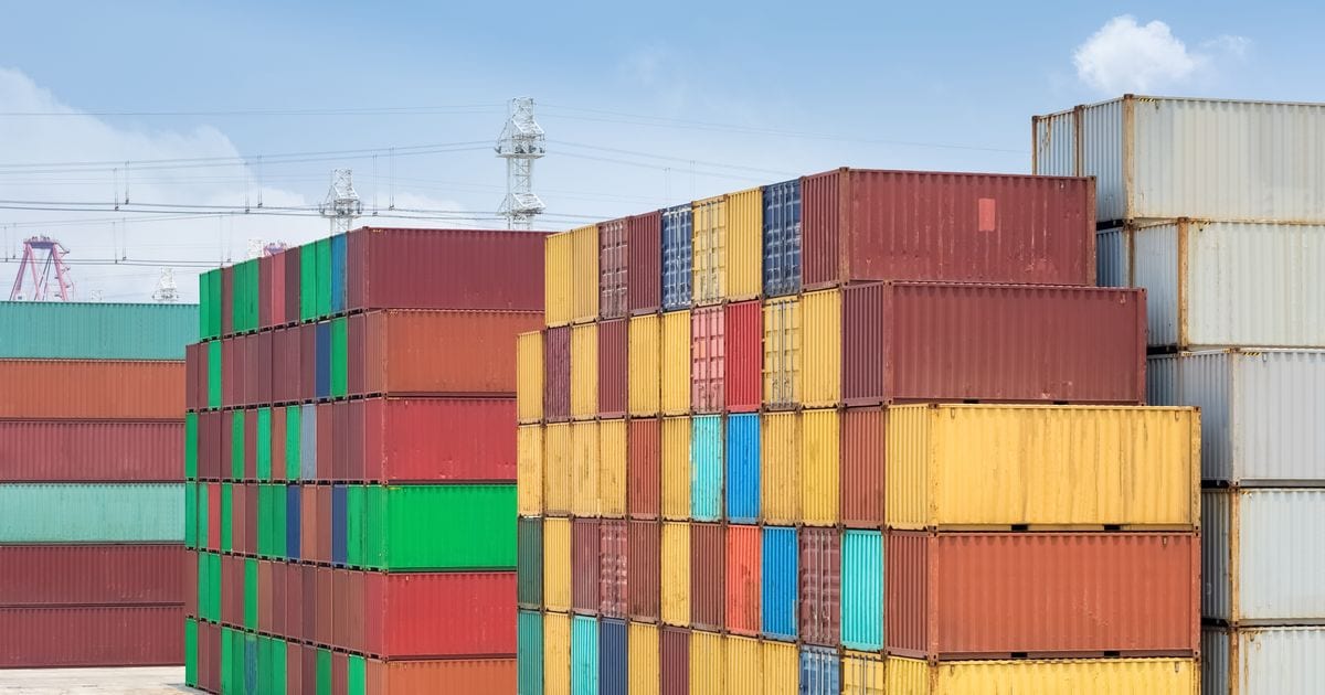 Coloured shipping containers stacked in rows at a port